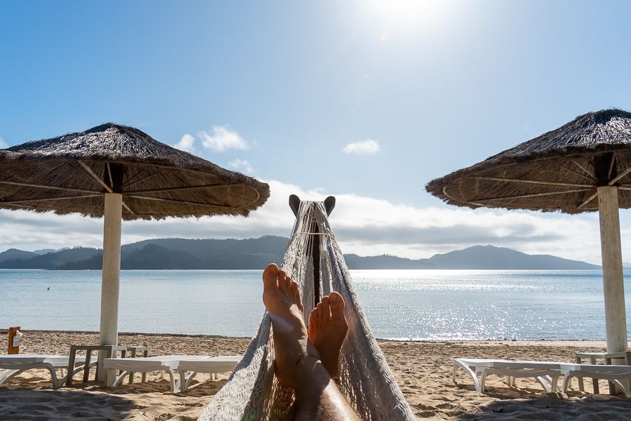 person lounging in a hammock by beach on hamilton island