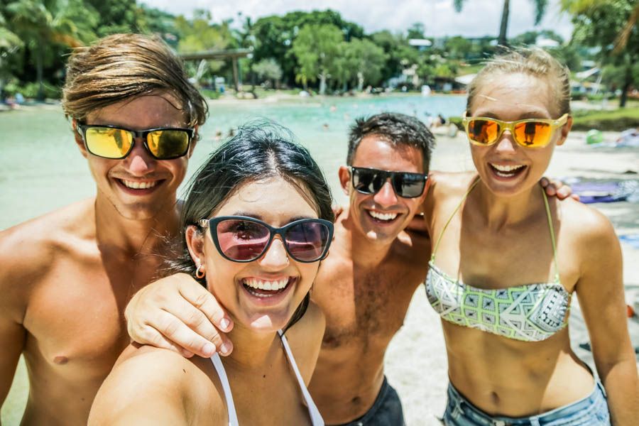 Four people wearing sunglasses taking a selfie at the Airlie Beach Lagoon