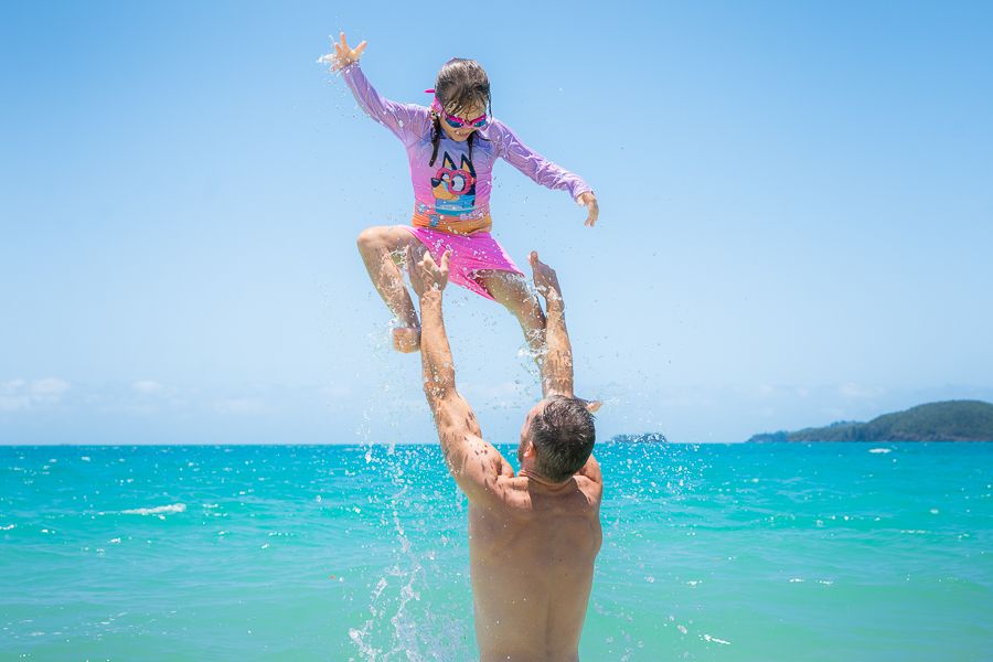 Whitsundays Family Beach Day father throwing daughter into the air at the beach