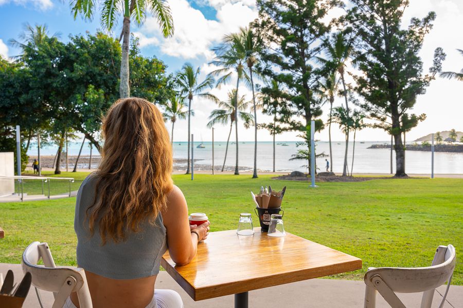 Airlie Beach Cafes a woman sitting at a cafe overlooking the ocean