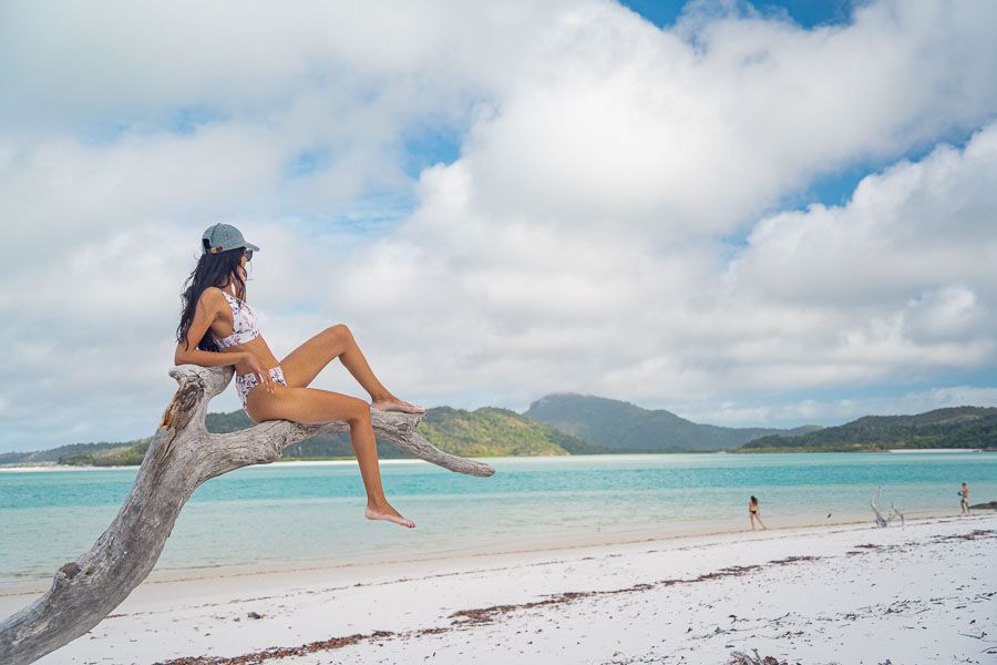 girl lounging on a tree at Whitehaven Beach whitsundays