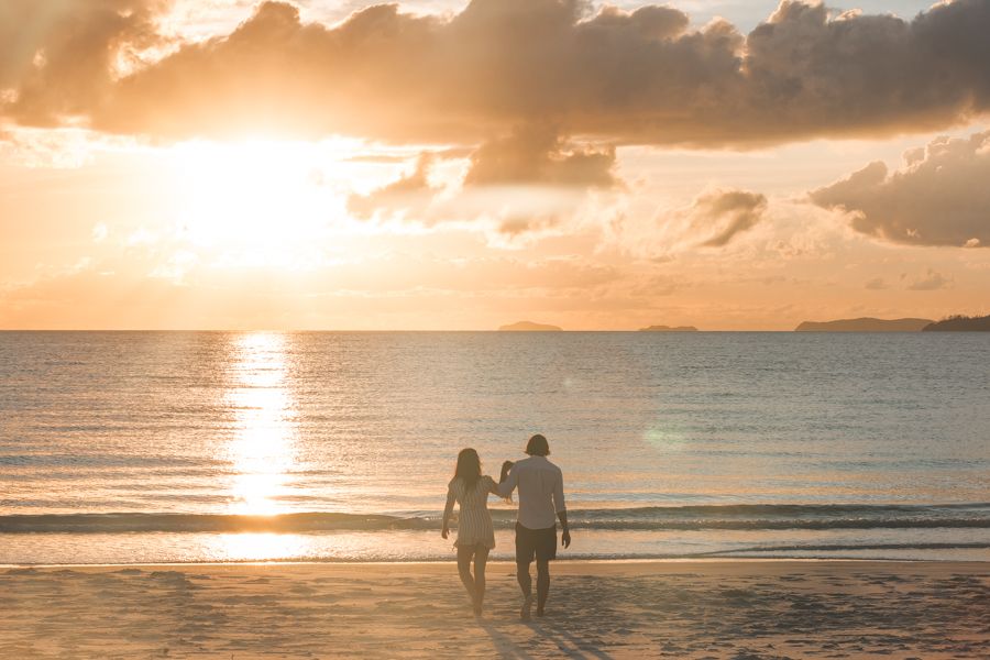 Couple walking along Whitehaven Beach at sunrise