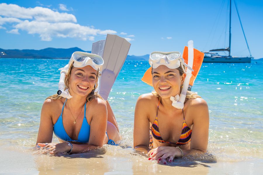 Whitsunday Islands two women in snorkel masks and wins on the beach