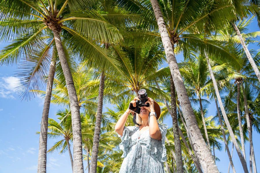 girl taking photos of palm trees around cairns