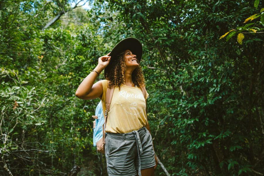 Girl walking in the bush with a hat and backpack