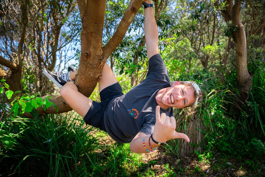 man hanging from a tree on an outdoor hike