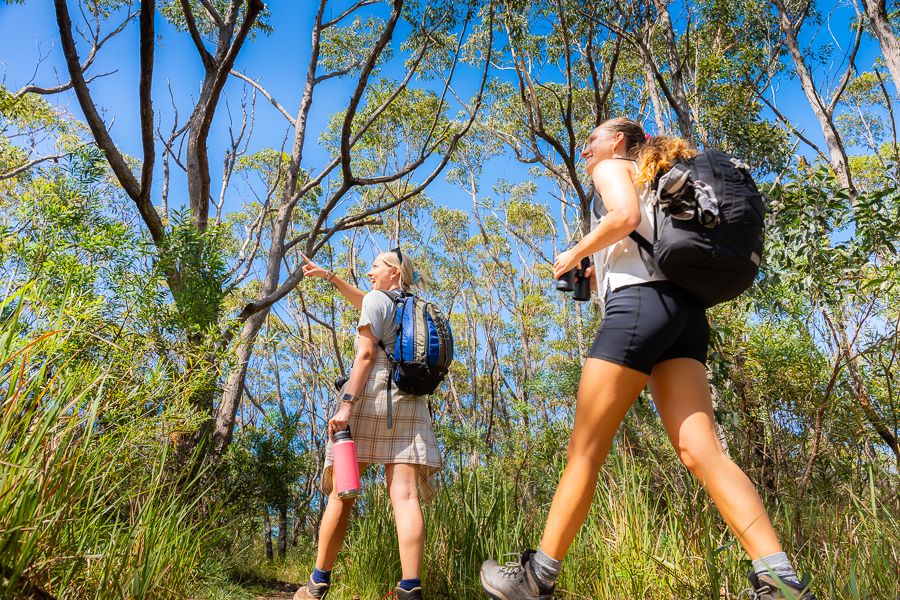 two girls hiking with backpacks in the forest