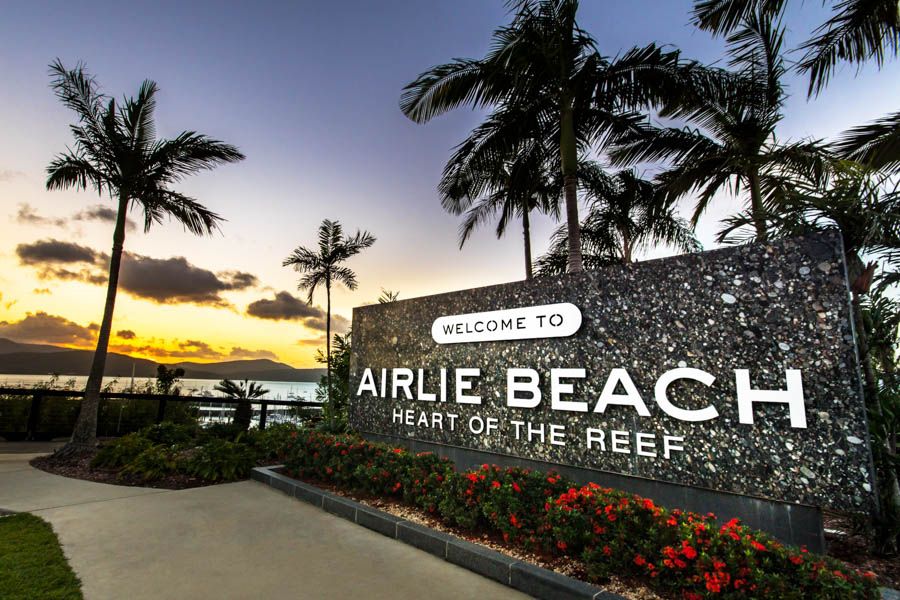 Airlie Beach sign at sunset with palm trees