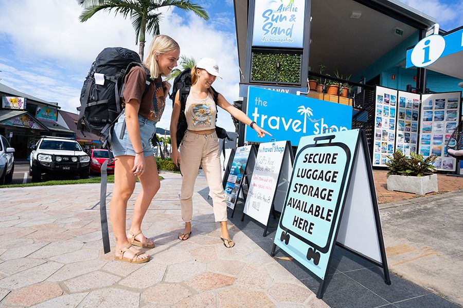 Two backpackers entering The Travel Shop to store their luggage, Airlie Beach.