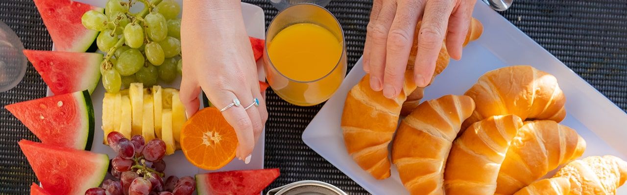 Whitsunday Blue Breakfast An aerial shot of a hand reaching for a fruit on a fruit platter